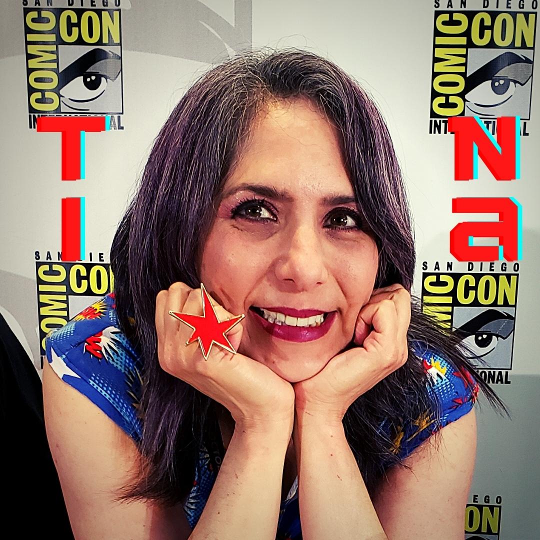 Tina smiles with her chin in her hands at the Comic-Con convention.