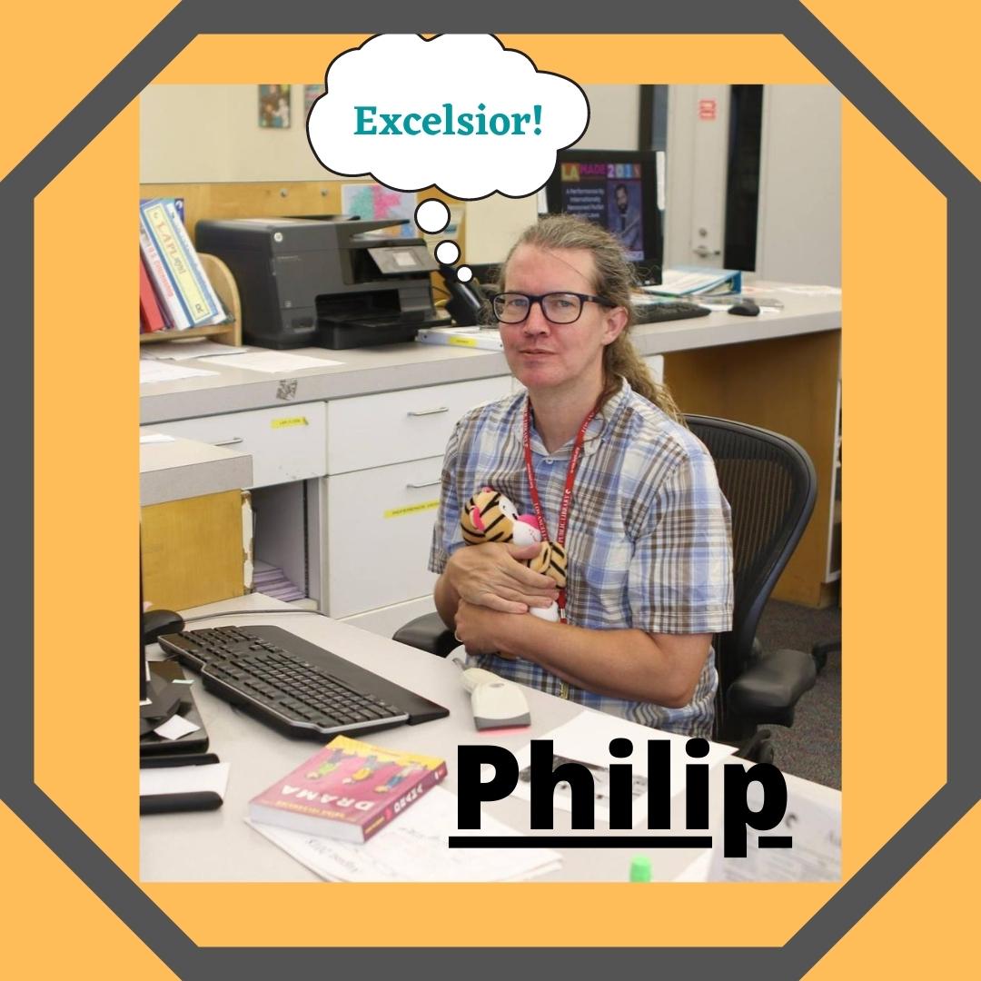 Philip sits at his desk at the library clutching a stuffed tiger.