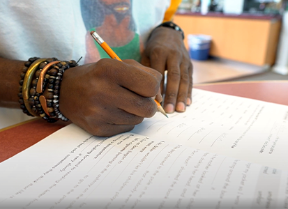 A student's hands over a literacy workbook.