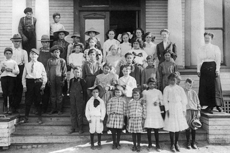 Young students pose for a class photo outside of the wooden schoolhouse of the Lemon School in Puente