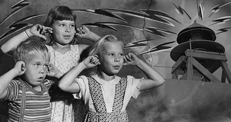 3 kids plug their ears from fireworks noise.