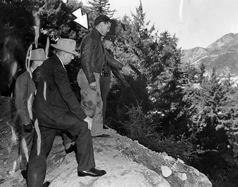 Laurel H. Crawford, indicated by arrow, is shown with deputy sheriffs standing on the edge of the precipitous 1000-foot slope
