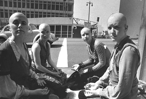 Bald women sit on the sidewalk outside the Manson trial