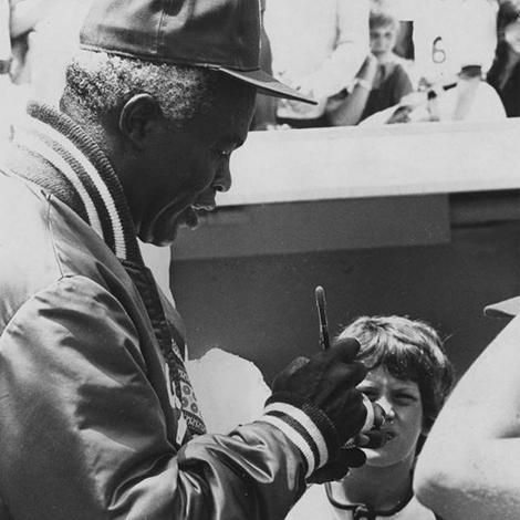 Jackie Robinson signing a baseball