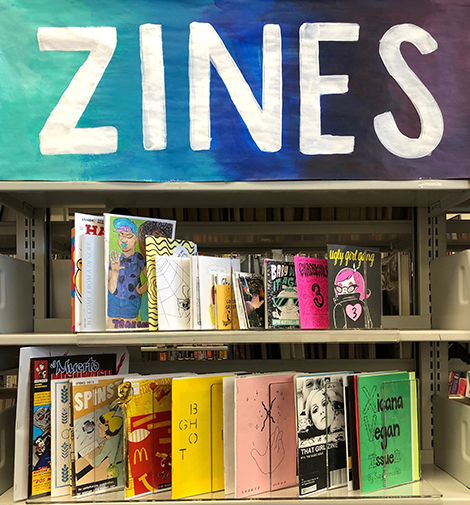 zine sign, and zines on a shelf