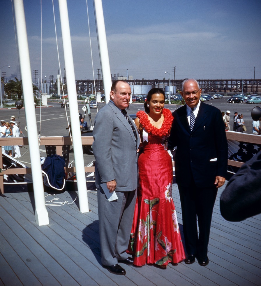 Matson “Girl” and event hostess Virginia Tibbetts posing for photographers. She is seen here with Matson executive Randolph Sevier and Farrant L. Turner (right)