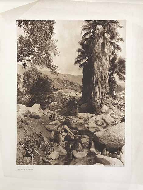 a photograph of a Native American woman gathering water from a stream in Andres Canyon