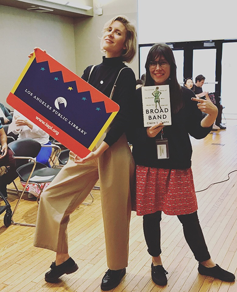 Claire L. Evans holding a library card and Edendale Branch Adult Librarian Angi Brzycki