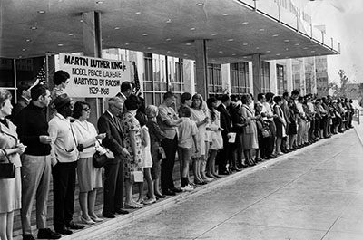 People lined up in front of a sign honoring Martin Luther King, Jr. 