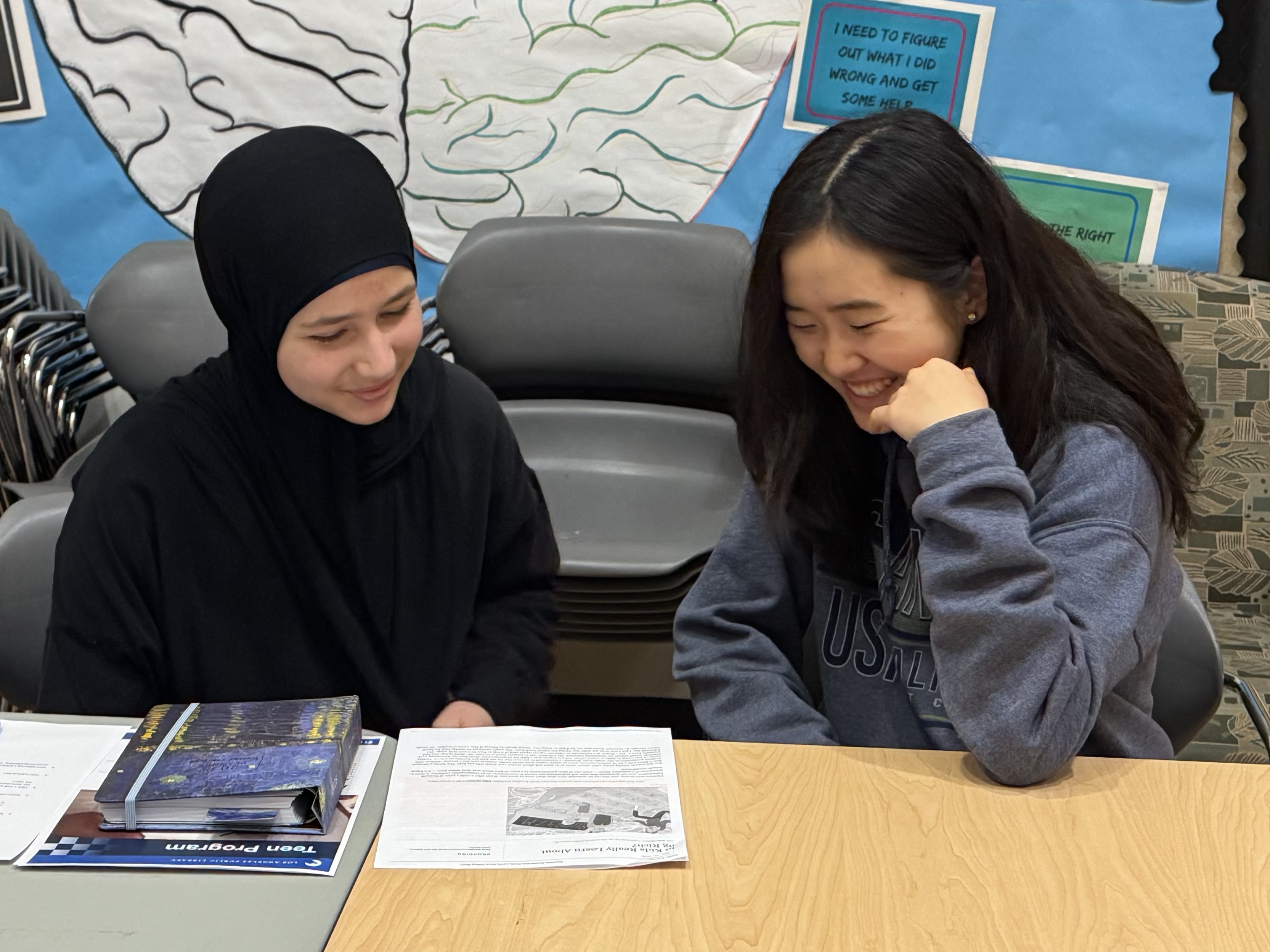 two teens looking at a book together
