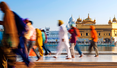 multicultural crowd walking in front of a landmark 