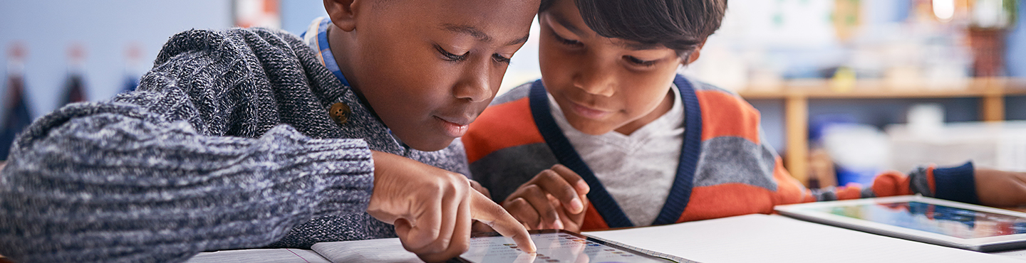 two kids learning on a device