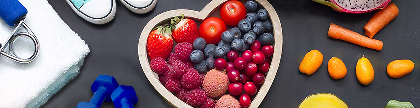 fruit arranged in a heart, vegetables, and exercise equipment for healthy living