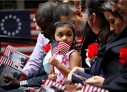 A young girl holds an American flag at a citizenship ceremony.