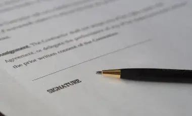 single page of a contract with a black pen on top