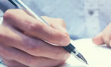 Hands writing in a notebook.