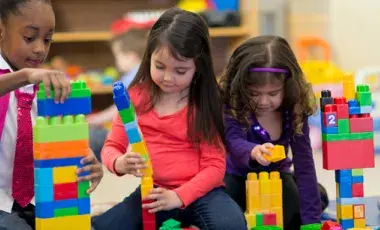 Three girls playing with toy blocks
