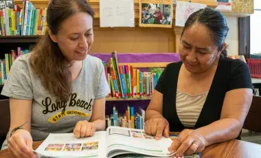 An instructor and a student review a workbook.