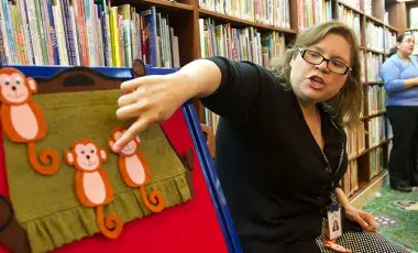librarian points to a felt monkey on a flannel board story