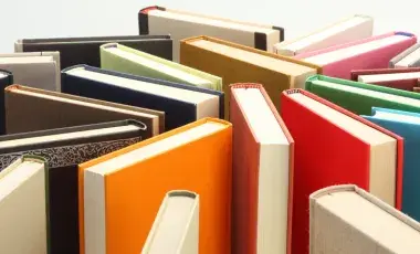 A group of different colored books standing upright clustered together.