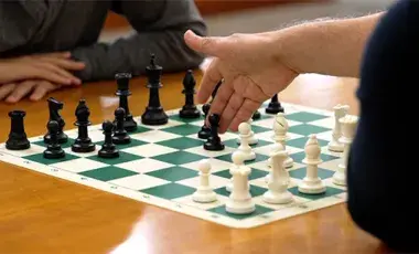 a game of chess being played by two players on a wooden table