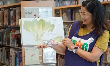 Woman wearing STAR vest holding up a book