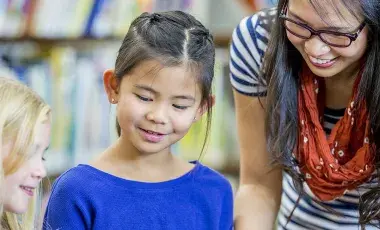 Two children listens to an adult reading to them