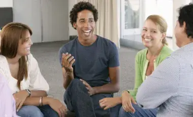 Group of adults sitting in chairs in a circle having a lively conversation