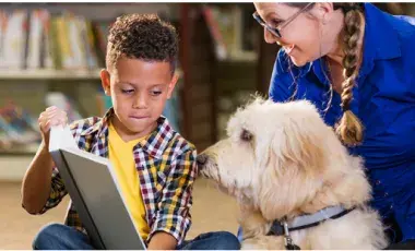 boy reading to dog with adult watching