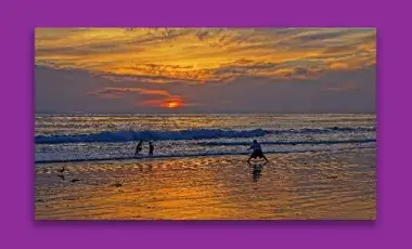 Three kids playing in the surf at sunset.