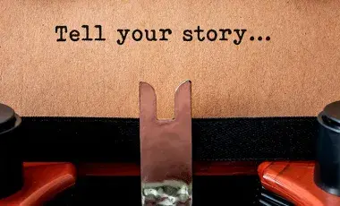 typewriter and text on page that reads "tell your story..."