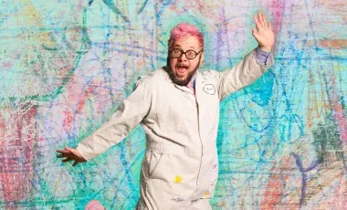 ricky rainbow beard - a person with pink hair jumping against a colorful background