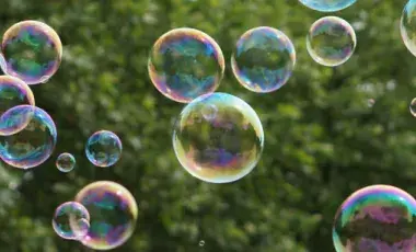 bubbles floating through the air in front of greenery