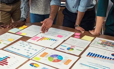 people leaning over a table looking at business spreadsheets