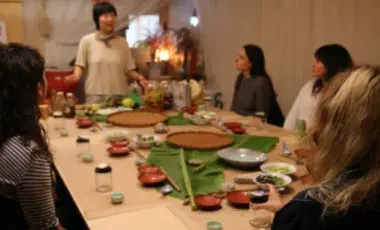 a group of people sitting around a table listening to Chef Jess Wang talk 
