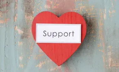 red heart with word support in black text
