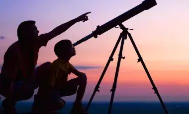 Adult and youth looking through a telescope at the night sky