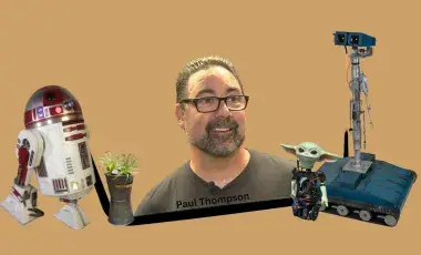 Image of Paul Thompson being surrounded by some of his robotic creations