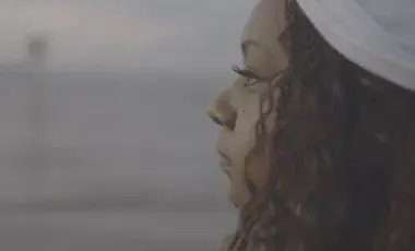 African american woman with a white headband stares out to sea