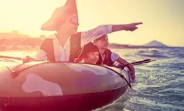 kids dressed as pirates on a rubber boat on water