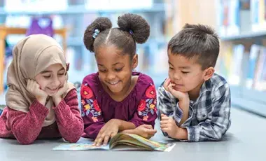 three kids reading a book together