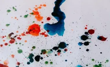 Different colors of paint splashed onto white paper