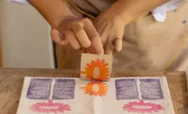 A person stamping a canvas bag at a table