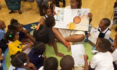 woman reading an oversized book to a group of children