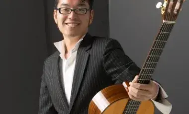 A man holding a guitar and looking at the camera 