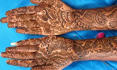 two hands laying flat covered in intricate henna designs