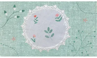 Textured light green and white fabric with flowers and green leaves embroidered on it.