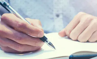 hands writing in notebook
