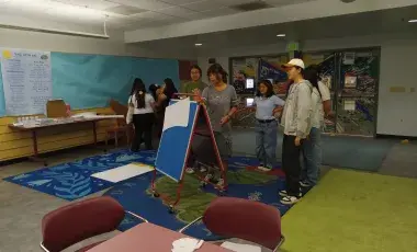 Teen council members stand around a white board brainstorming ideas