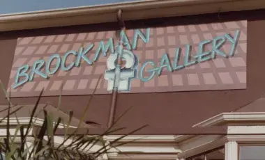 "Brockman Gallery" sign painted in blue over pink background